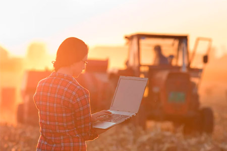 Una dona amb un ordinador portàtil i un tractor de fons